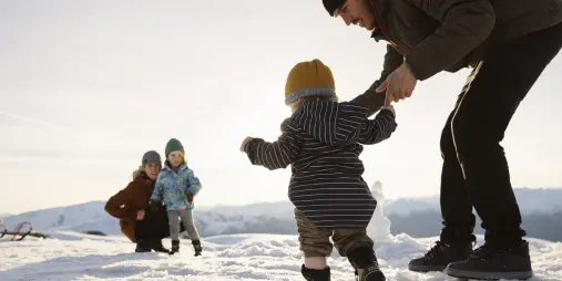 Family enjoying snow play at Cardrona Alpine Resort with children and toddlers in a winter setting