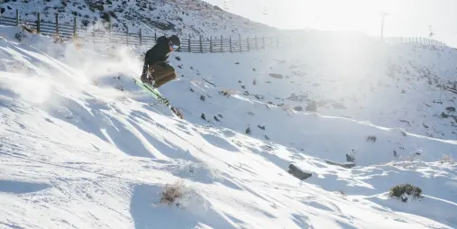 Skier carving a turn in fresh snow on opening day at Treble Cone ski area in Wānaka