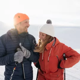 Happy couple holding ski poles against snowy alpine backdrop in Wānaka winter