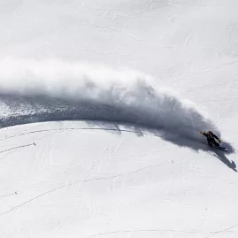Skier carving sharp turn through fresh snow on Wānaka alpine trail