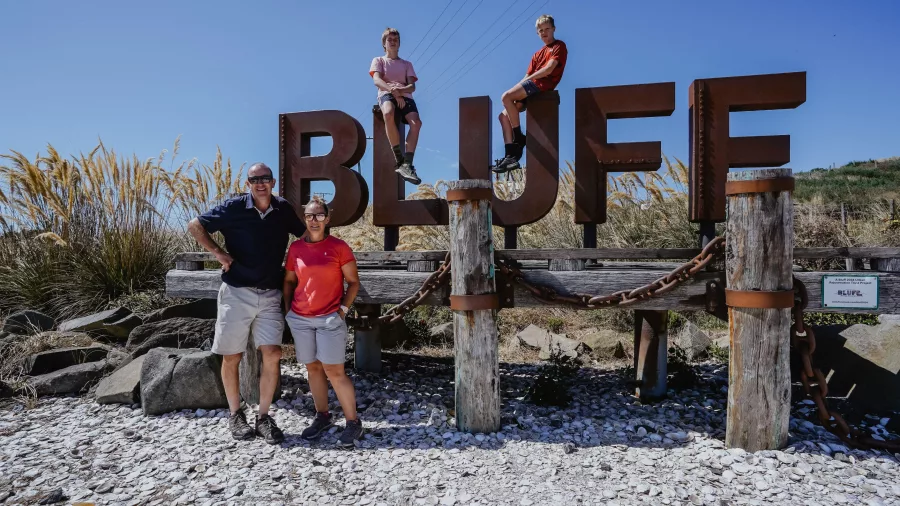 Family posing at Bluff welcome sign on a sunny day