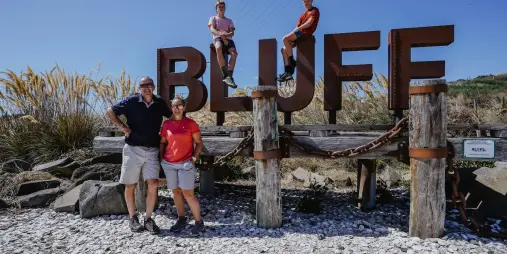 Family posing at Bluff welcome sign on a sunny day