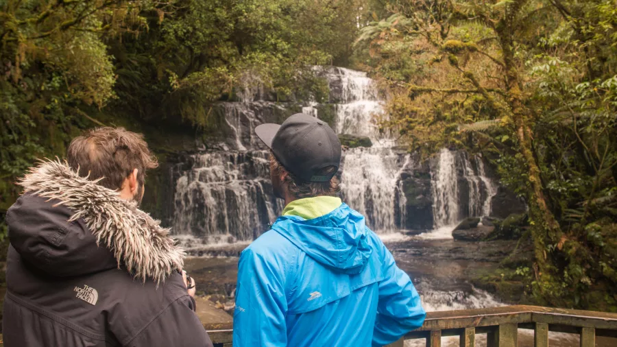Visitors enjoying the view from Purakaunui Falls viewing platform in The Catlins, Southland, New Zealand