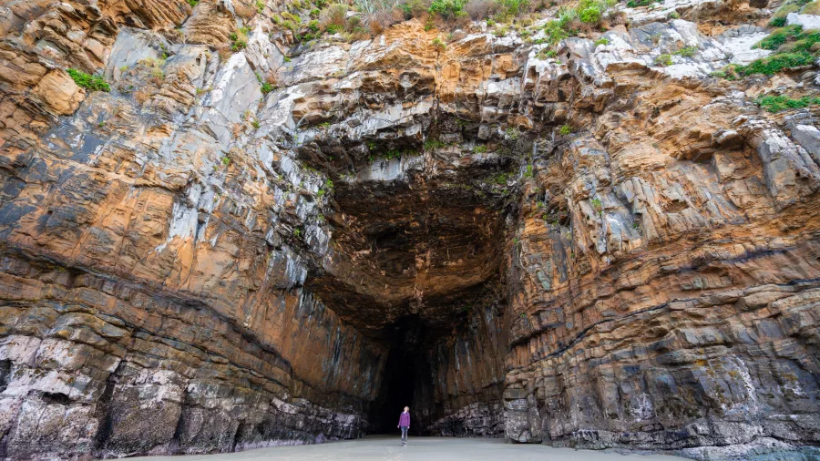 Person standing at the entrance of Cathedral Caves in The Catlins, Southland, New Zealand