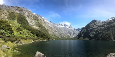 Panoramic view of Lake Marian surrounded by snow-capped mountains in Fiordland National Park, Southland New Zealand