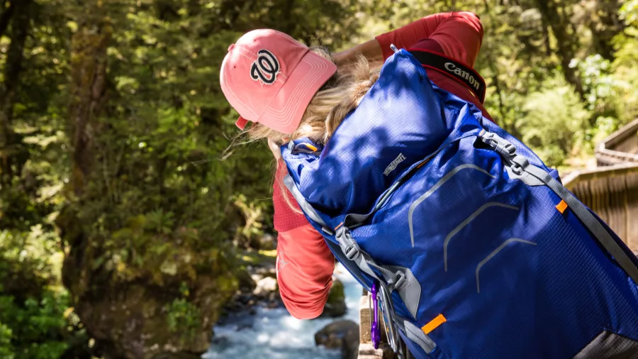 Hiker photographing turquoise river along Lake Marian Track, Fiordland National Park, Southland New Zealand
