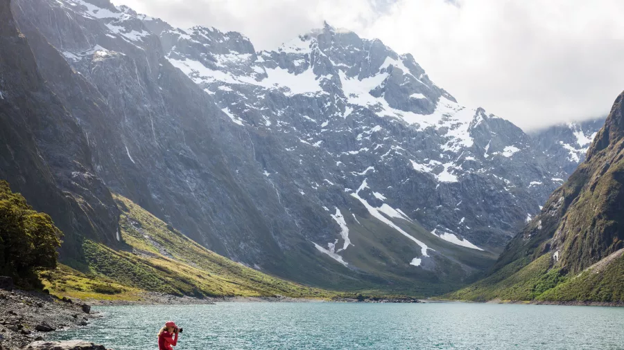 Snow-covered mountains rising above Lake Marian on a sunny day in Fiordland National Park, Southland