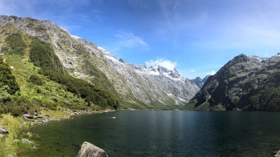 Panoramic view of Lake Marian surrounded by snow-capped mountains in Fiordland National Park, Southland New Zealand