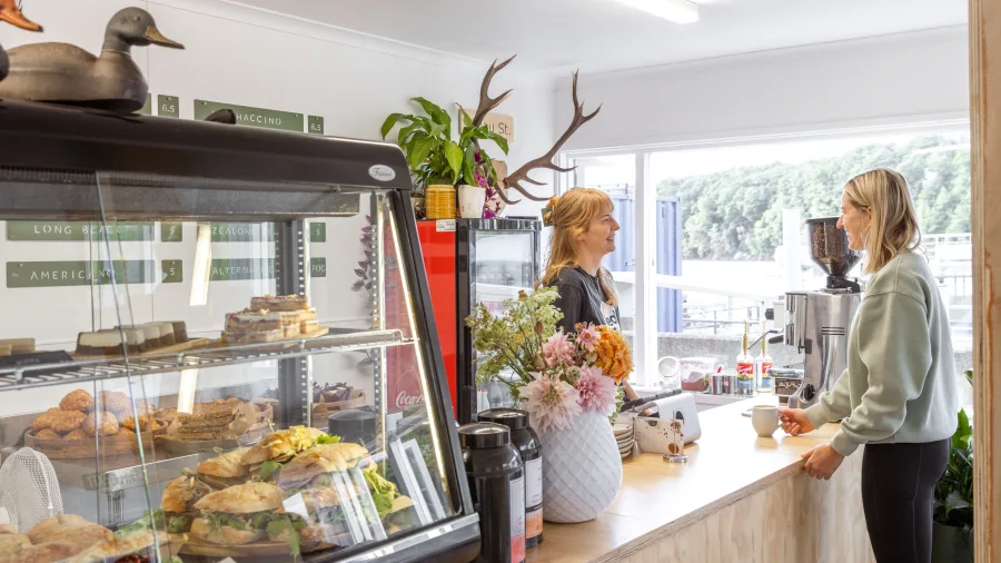 Customer ordering coffee at Waiau Street Café in Manapouri, known for fresh cabinet food and friendly service.