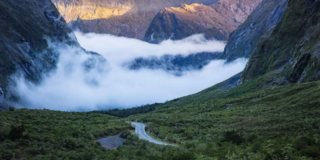 Mist rolling through a mountain valley along Milford Road in Southland, New Zealand