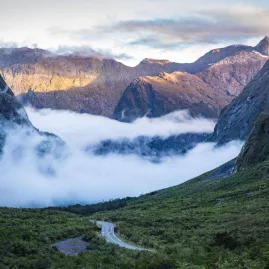 Mist rolling through a mountain valley along Milford Road in Southland, New Zealand