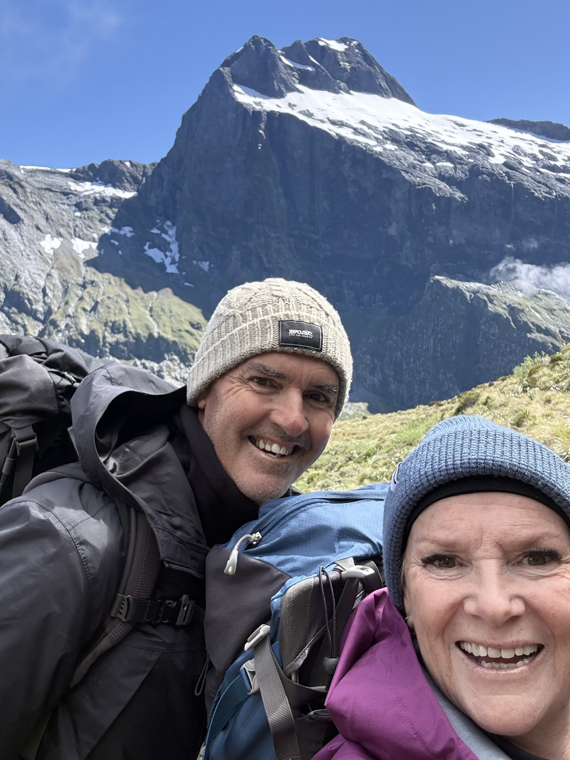 Two walkers with packs stopping along the Milford Track with mountain scenery near Mackinnon Pass