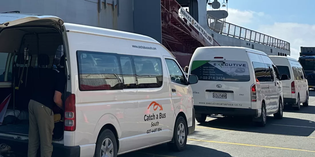 Catch a Bus South and other shuttle vans lined up near the ferry terminal for Stewart Island departures from Bluff.