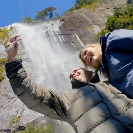 Couple taking a selfie near a powerful waterfall in Milford Sound