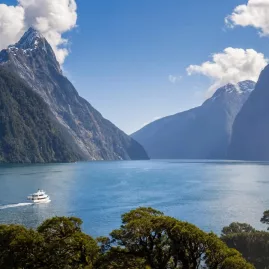 Cruise boat sailing through Milford Sound with Mitre Peak and dramatic fiord scenery