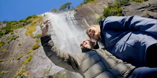 Couple taking a selfie near a powerful waterfall in Milford Sound