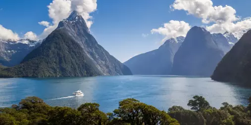 Cruise boat sailing through Milford Sound with Mitre Peak and dramatic fiord scenery
