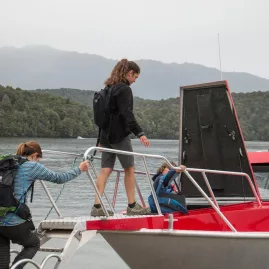 Hikers boarding a red water taxi at Brod Bay on Lake Te Anau for the Kepler Track.
