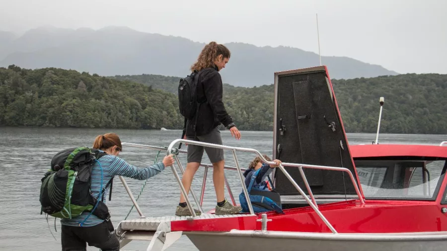 Hikers boarding a red water taxi at Brod Bay on Lake Te Anau for the Kepler Track.