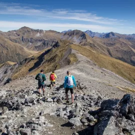 Hikers descending along the rocky ridgeline of Mount Luxmore on the Kepler Track.