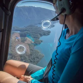 Woman enjoying a scenic helicopter flight over Lake Te Anau before hiking the Kepler Track.