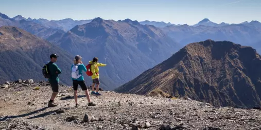 Hikers pausing at a scenic viewpoint overlooking Fiordland mountains.