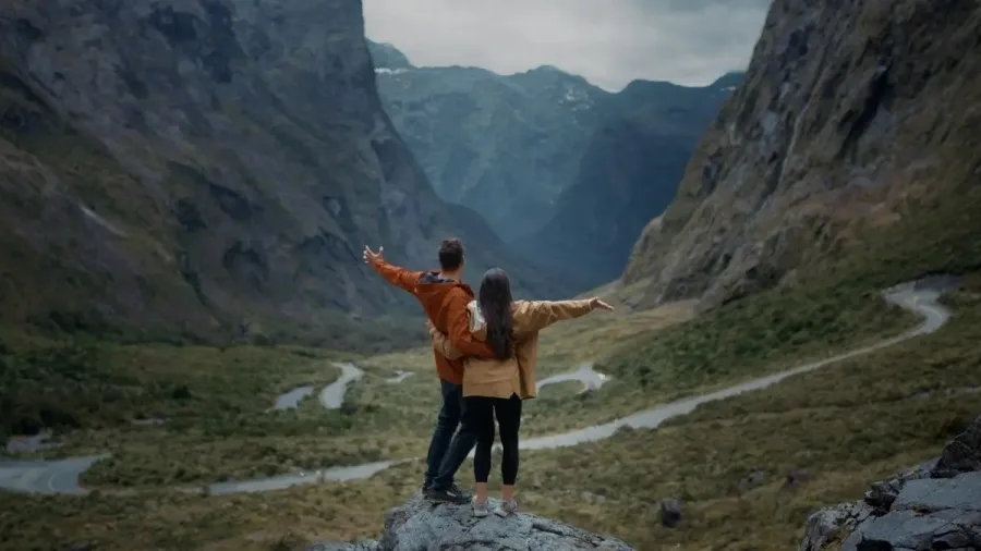 Couple embracing at Monkey Creek with dramatic mountain views in Fiordland.