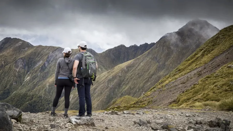 Couple on Routeburn Track looking towards Harris Saddle under dramatic skies.