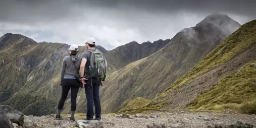 Couple on Routeburn Track looking towards Harris Saddle under dramatic skies.