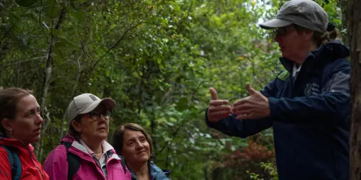 Local guide explaining Stewart Island's native forest and wildlife to visitors on a guided walking tour.