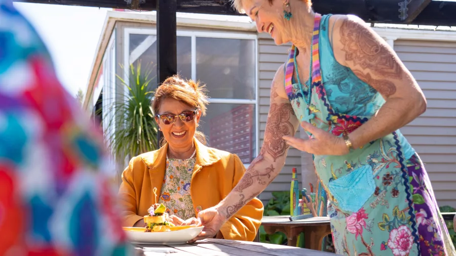 Café host serving brunch to a smiling customer at Lemonwood Cave in Oakura, Taranaki