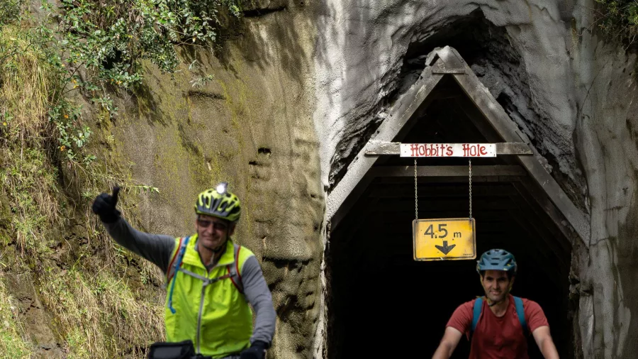 Cyclists riding through Moki Tunnel, also known as Hobbit’s Hole, on the Forgotten World Highway