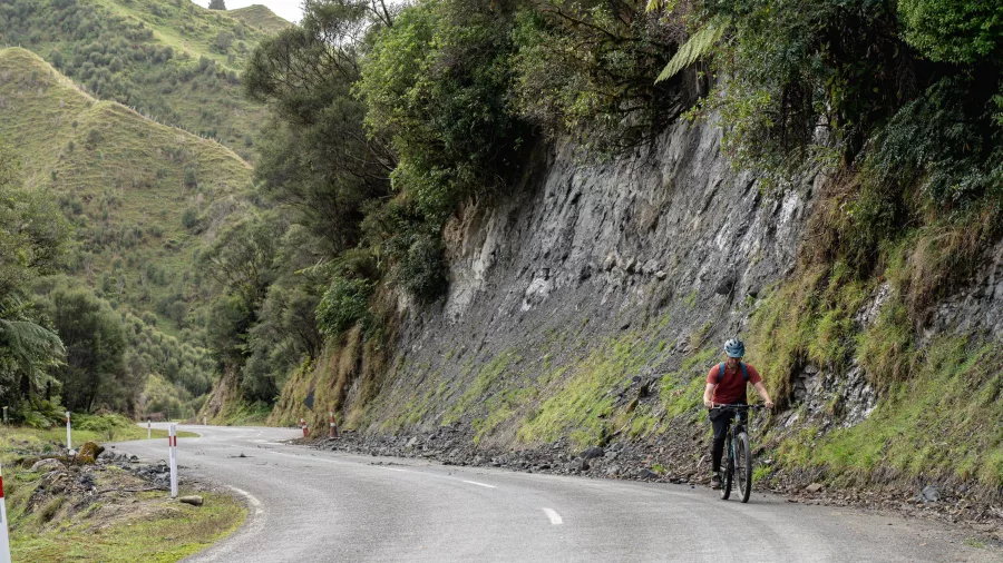 Cyclist riding uphill along a winding road on the Forgotten World Highway