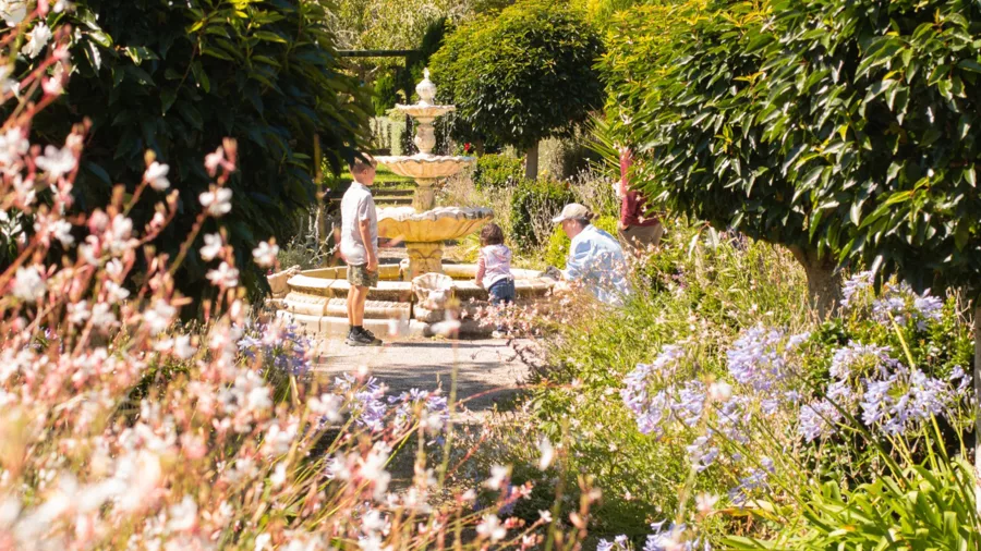 Family enjoying the garden fountain surrounded by flowers at Waiongana Garden in Taranaki
