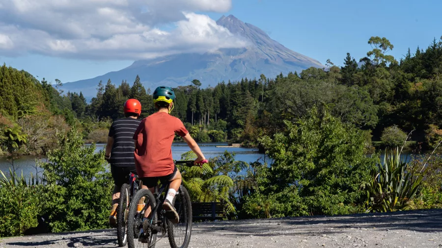 Two mountain bikers at Lake Mangamahoe with Mount Taranaki rising in the distance