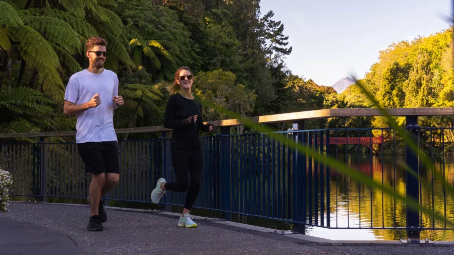 Couple jogging along a lakeside path in Pukekura Park, New Plymouth