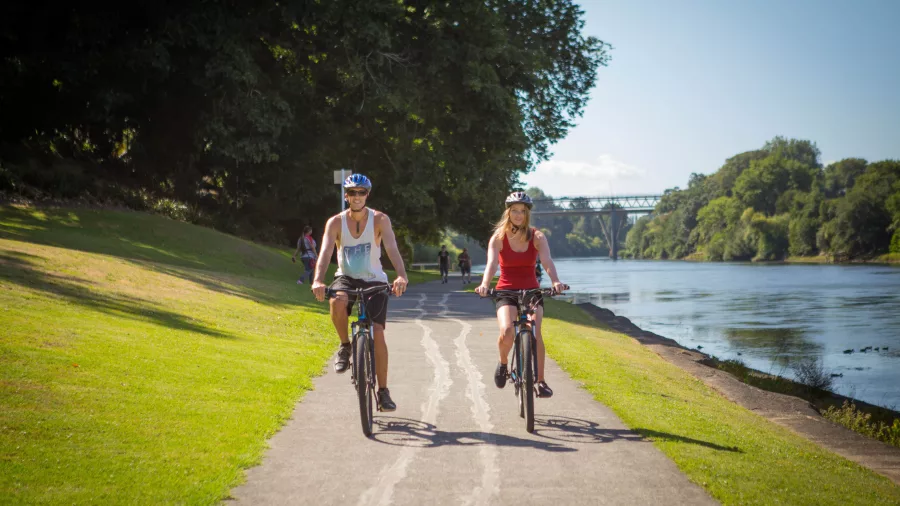 Couple cycling along the riverbank on the Te Awa River Ride in Hamilton