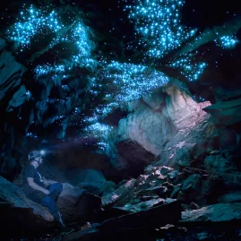 Guest wearing a headlamp sits beneath glowworms inside a limestone cave on a Glowing Adventures private tour in Waitomo