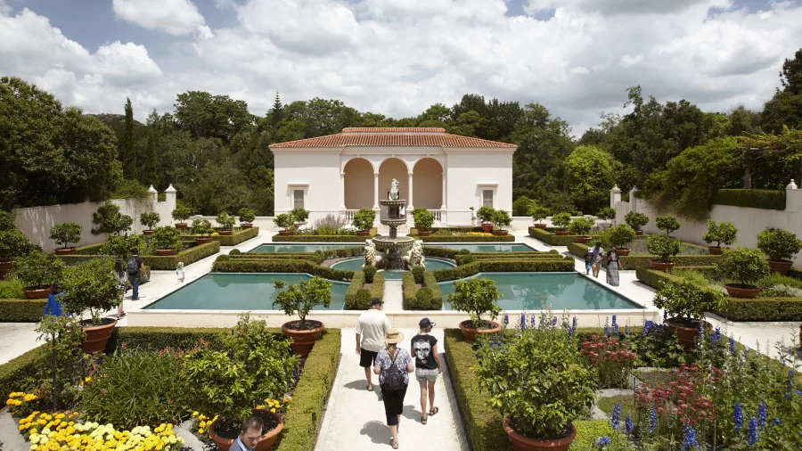 Visitors walking through the formal Italian Renaissance Garden at Hamilton Gardens, surrounded by geometric pools, trimmed hedges, and potted citrus trees