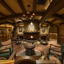 Cosy interior of the Green Dragon Inn at Hobbiton featuring a fireplace, timber beams and rustic Hobbit-style furniture