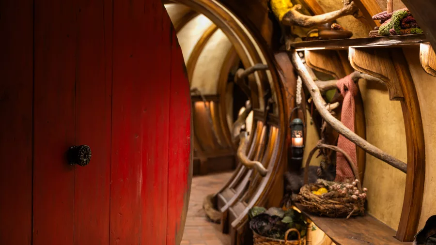 Red round door opening into Bagshot Row Hobbit hole with rustic interior decor
