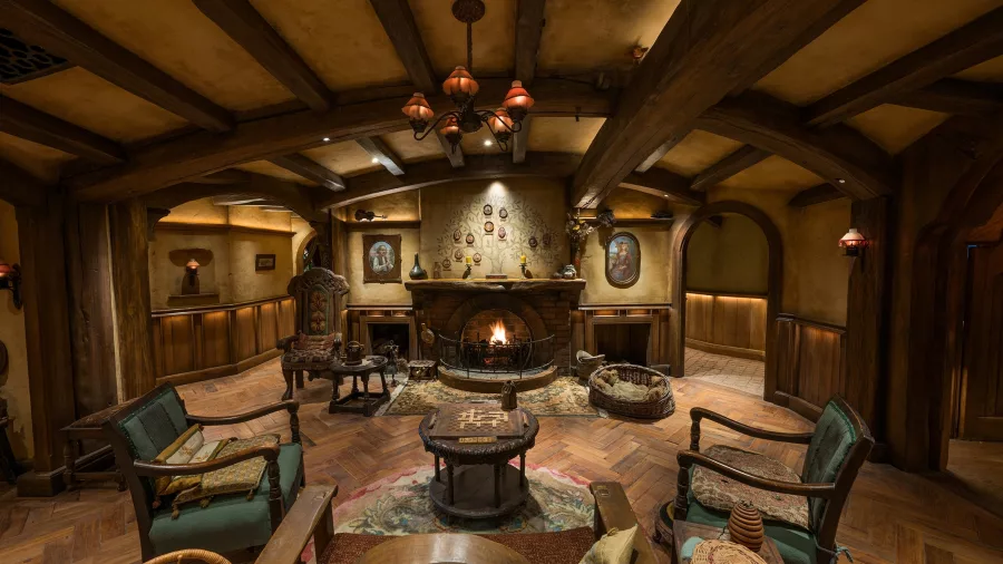 Cosy interior of the Green Dragon Inn at Hobbiton featuring a fireplace, timber beams and rustic Hobbit-style furniture