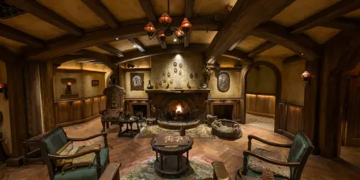 Cosy interior of the Green Dragon Inn at Hobbiton featuring a fireplace, timber beams and rustic Hobbit-style furniture