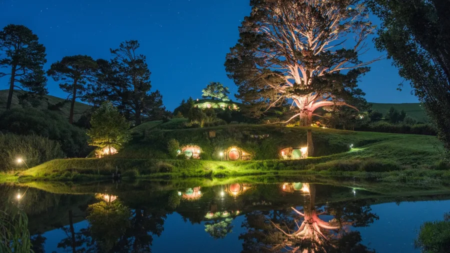 Night view of Hobbiton Movie Set in Matamata with lit hobbit holes and reflections on the water