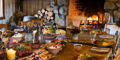 Banquet table filled with hobbit-style food and desserts set by a roaring fireplace at Hobbiton Movie Set