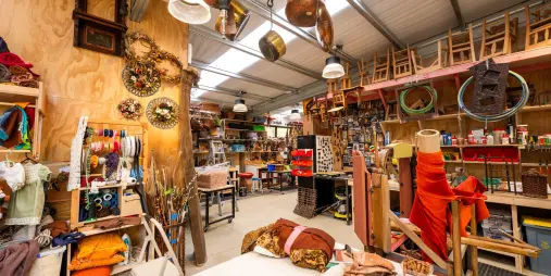 Inside the Hobbiton prop workshop, filled with tools, ribbons, and crafting supplies