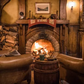 Warm fireplace and rustic seating inside the Green Dragon Inn at the Hobbiton Movie Set in Matamata, New Zealand