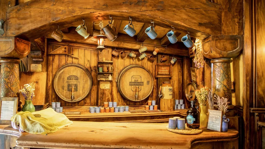 Rustic bar counter with wooden barrels and mugs at the Green Dragon Inn in Hobbiton Movie Set Matamata