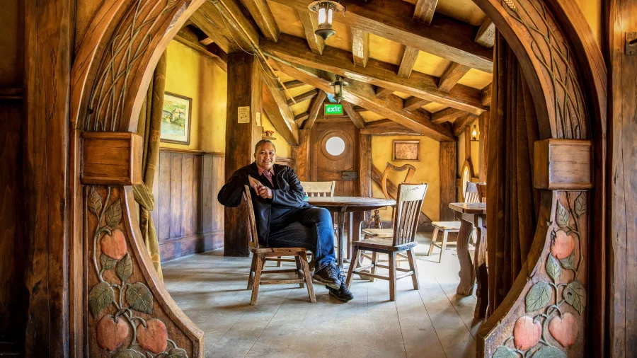 Visitor sitting inside the cosy wooden interior of the Green Dragon Inn at Hobbiton Movie Set in Matamata