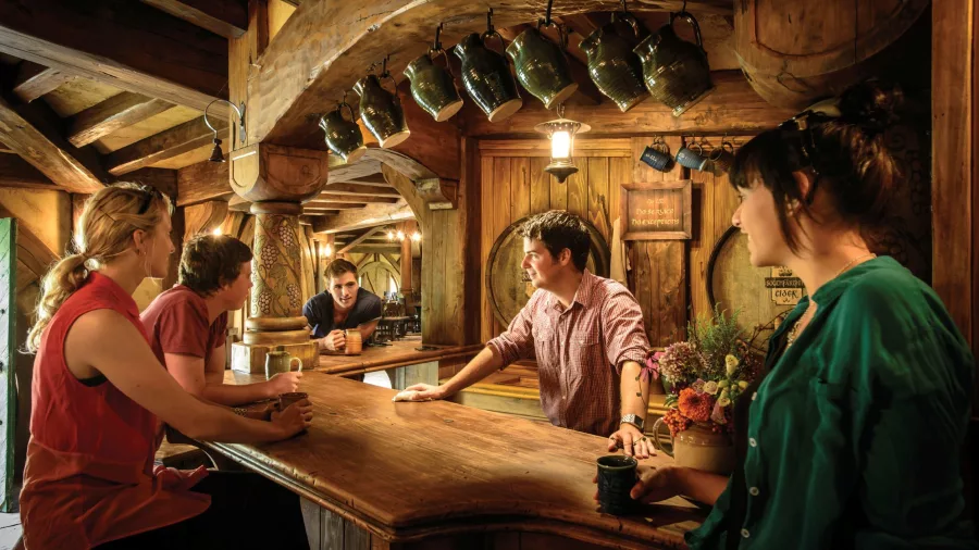 People enjoying drinks inside the cosy Green Dragon Inn at Hobbiton Movie Set